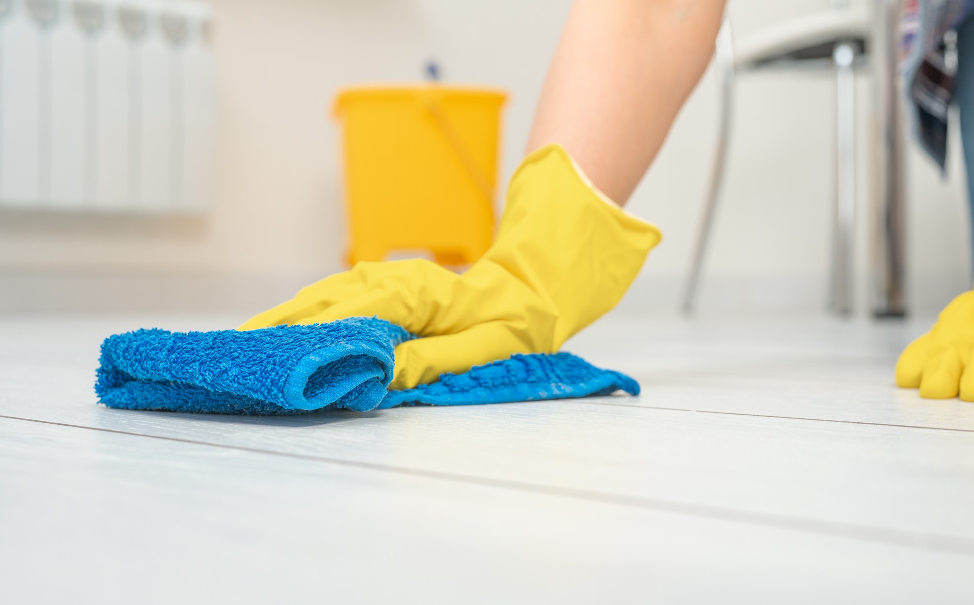 Servicio de limpieza profunda. Limpiador profesional de lavado de suelo blanco en salón de apartamento. Las manos femeninas en guantes limpian el piso blanco con la limpieza de texto. Concepto de servicio de limpieza